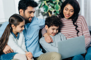 cheerful hispanic family looking at laptop at home