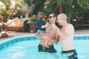 two-men-and-a-baby-at-the-swimming-pool-in-summer_t20_kLzpWP